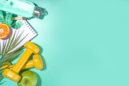 Spring, summer slimming season concept. Sport bottle with water, fitness dumbbells, beach lounger decor, measuring tape, notepad, apple, sliced orange on light blue white background. Flatlay copy space top viewの写真素材
