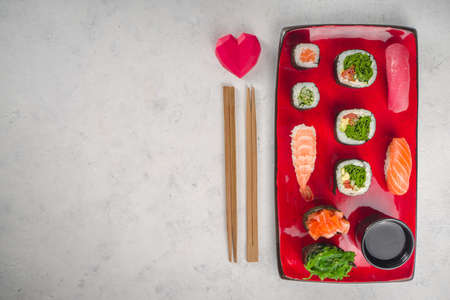 Valentine day festive dinner idea. Menu, invitation background for Valentine day sushi roll set, with heart shaped decor and rose flowers bouquet. Top view with copy space for textの写真素材