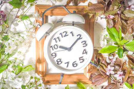 Spring Forward Time, Savings Daylight Concept with Alarm Clock and Spring Garden Flowers on wooden...