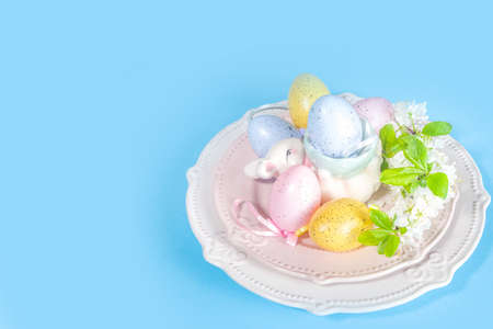Easter table setting decoration, with colorful Easter eggs, spring garden blossom flower, bunny...