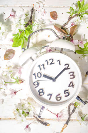Spring Forward Time, Savings Daylight Concept with Alarm Clock and Spring Garden Flowers on wooden...