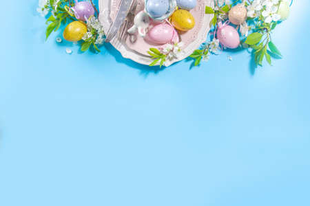 Easter table setting decoration, with colorful Easter eggs, spring garden blossom flower, bunny...