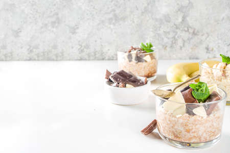 Set various fruit overnight oatmeal. Oats porridge with strawberry, bananas, chocolate, nuts in small portion jars. Summer breakfast oatmeal. Healthy vegan diet snack.の写真素材