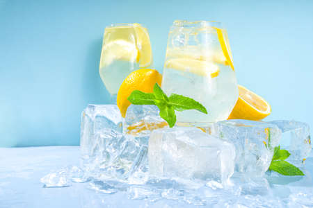 Traditional summer cold refreshing cocktail lemonade, with lemon slices and lots of crushed ice and iced pedestals on blue backgroundの写真素材
