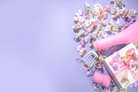 Cute high-colored Valentine day background, with pink colored champagne bottle, spring blossom flowers, little heart decor, on violet very peri color background flatlay copy spaceの写真素材