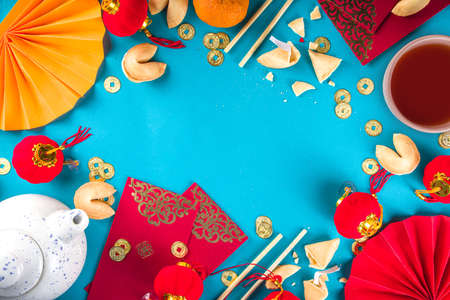 Chinese new year background. Red and golden yellow flatlay with traditional Chinese new year decor, envelopes with wishes, gold coins, fans, Chinese lanterns, oranges and teaの写真素材
