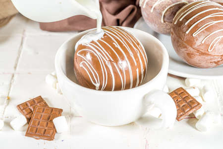 Homemade hot chocolate bomb with marshmallow and chocolates and nuts, Cooking making cocoa with chocolate ball, dropping coca bomb in milkの写真素材