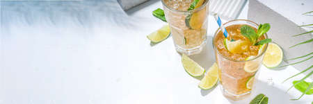 Cuba Libre, long island iced tea cocktail with strong alcohol drink, cola, lime and ice in two glass, cold longdrink mocktail on light blue tiled backgroundの写真素材