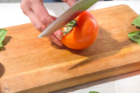 Close-up of cutting slicing fresh tomatoes. Woman's hands cut with knife fresh tomato vegetables