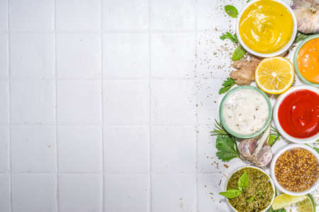 Assortment of different classic sauces and dips in sauceboats. Mayonnaise, ketchup, tartare, mustard, pesto, sour cream, barbecue sauces with spices, herbs, lemonの写真素材
