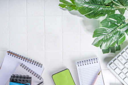 office desk background. Laptop keyboard, smartphone and various work supplies on office white desk background flat-lay copy spaceの写真素材