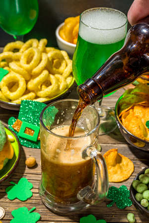 St Patrick`s holiday party invitation, bar menu background. Irish St Patrick`s day beer, ale glasses, snacks, appetizer, green burger, wooden bar table with shamrock, clover, coins, leprechaun hatの写真素材