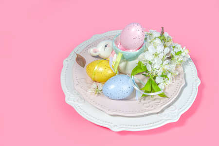 Easter table setting decoration, with colorful Easter eggs, spring garden blossom flower, bunny...