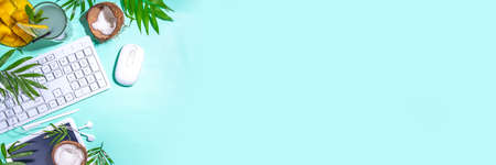 Summer work, freelancing, combining work and leisure vacation concept. Office flatlay with keyboard laptop, tablet, mouse, notepad, palm leaves, tropical fruits and cocktail, banner header top viewの写真素材