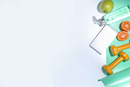 Spring, summer slimming season concept. Sport bottle with water, fitness dumbbells, beach lounger decor, measuring tape, notepad, apple, sliced orange on light blue white background. Flatlay copy space top viewの写真素材