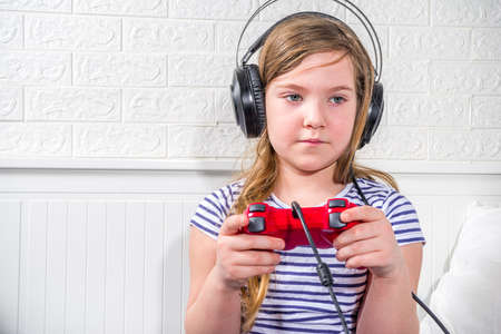 Kids gamers concept. Caucasian preteen little child girl holding joystick playing video games at...
