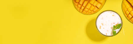 Fresh mango smoothie, yogurt, milkshake or smoothie with half slice of mango on high-colored bright...