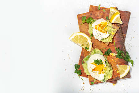 Healthy diet sandwiches for breakfast, snack. Toast with guacamole avocado salsa and poached eggの写真素材