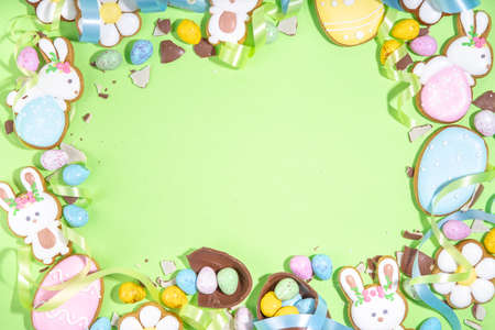 Happy Easter colorful flatlay. Colorful sugared and chocolate Easter eggs, sugar glazed cookies with...