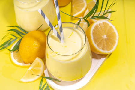 Creamy lemon fruit smoothie, yogurt ar milkshake, Sour sweet drink with fresh lemons on white yellow background copy spaceの写真素材