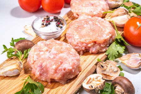 Burger cutlets from chicken, turkey ground meat. Raw patty minced white meat cutlets on a cutting board with spices, herbs for cookingの写真素材