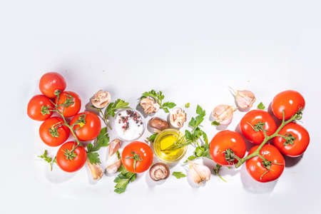 Food cooking background. Kitchen table background with spices, herbs, vegetables. Parsley, onion, garlic, tomatoes, salt, olive oil on a white background top view flatlay copy spaceの写真素材