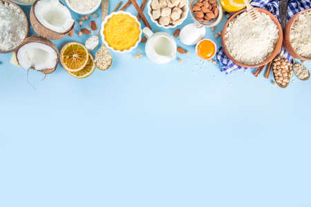 Cooking baking background frame background. Selection of various gluten free flour and ingredients, for sweet and bread bakery, on colorful blue kitchen table with utensils, eggs, sugar, cinnamonの写真素材