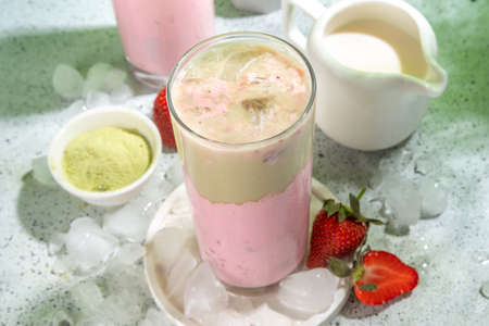 Natural healthy summer drink. Diet organic strawberry and matcha latte cocktail, with fresh strawberry and ice, on a white light green backgroundの写真素材