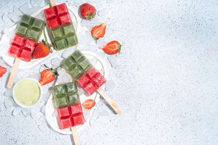 Dairy free green matcha and strawberryice creams. Vegan ice creamwith green matcha tea powder and dresh strawberry juice, Summer healthy organic dessert on white concrete backgroundの写真素材