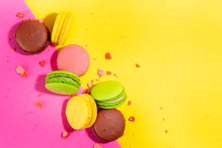 Bright colorful (yellow, pink, green, brown) various flavor macarons sweet cookies on high-colored...