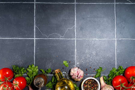 Cooking ingredients background. Spices, black pepper, garlic, onion, greens, tomatoes. olive oil on...
