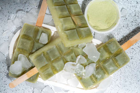 Vegetarian matcha green tea  . Vegan diet coconut matcha latte ice cream lollypops on white table...