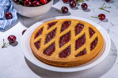 Homemade cherry pie, summer sweet cake with fresh raw cherry fruit on white background copy space
