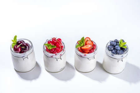 Variety of yogurts in portion glass jars. Healthy summer breakfast concept, with seasonal berry...