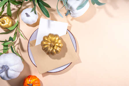 Fall seasonal table setting flatlay. Autumn seasonal holidays background in beige colors. White, orange, golden pumkins decor for thanksgiving, fall holidays, invitation menu backgroundの写真素材