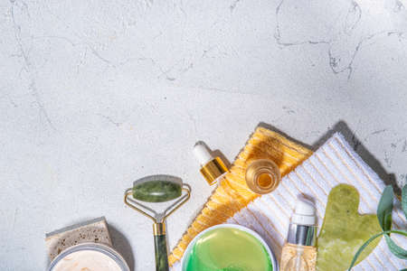 Nature anti-aging cosmetics, therapy massage. Asian beauty skin care. Jade roller, gua sha massager with various organic serum, gel, herbal extract, spa towels. Flat lay on white marble backgroundの写真素材