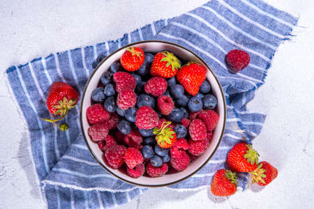 Fresh summer berry in white bowl with napkin on kitchen table. Ripe raw blueberry raspberry, strawberry copy spaceの写真素材