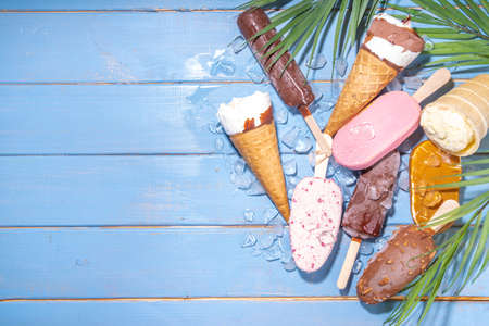 Set of various ice creams on black background. Assortment of ice cream cones on wooden blue beach backgroundの写真素材