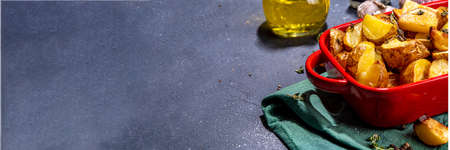 Slices of fried or baked potato wedges with herbs and spices in frying pan copy spaceの写真素材