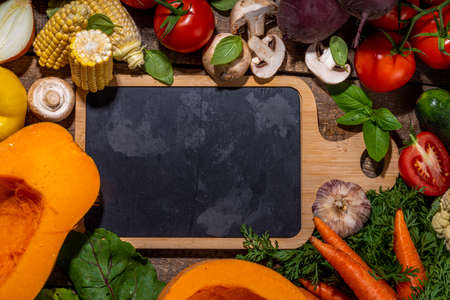 Autumn vegetable cooking background. Organic fall harvest farm vegetables, mushrooms. Various vegetarian ingredients set for cooking dinner on wooden kitchen background, top view copy spaceの写真素材