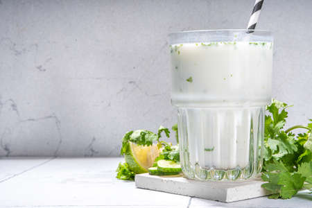 Fresh asian yogurt drink kefir, ayran in glass with smashed herbs. Ayran, homemade summer healthy cocktail with herbs, lime, cucumbers. Probiotic, postbiotic fermented dairy drinkの写真素材