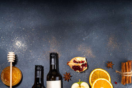 Different mulled wine ingredients set on black background, flat lay with wine bottle, cinnamon, apple, orange, anise star, simple autumn food drink cooking backgroundの写真素材