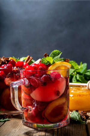 Christmas mulled wine with aromatic spices and citrus fruits and berries. Hot autumn winter fruity punch drink with red wine, on old rustic wooden background copy spaceの写真素材