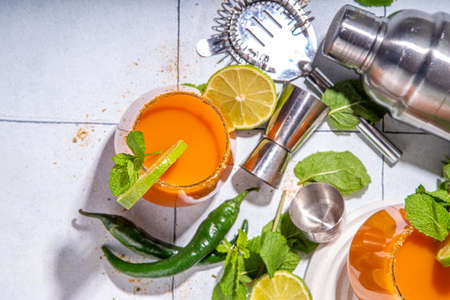 Carrot Ginger Margarita cocktail with lime, mint and hot chili pepper, original vegetable spicy drink on white tiled background copy spaceの写真素材