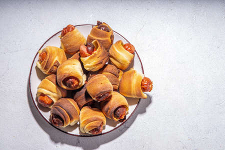 Oktoberfest party food. Pretzel hot dogs, puff pastry rolls with sausage and bacon, traditional Bavarian German Pigs in blanket on Oktoberfest decorated table backgroundの写真素材