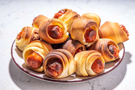 Oktoberfest party food. Pretzel hot dogs, puff pastry rolls with sausage and bacon, traditional Bavarian German Pigs in blanket on Oktoberfest decorated table backgroundの写真素材