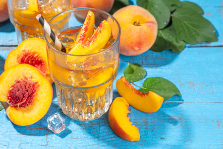 Homemade peach ice tea with ripe fresh peaches on high-colored blue wooden backgroundの写真素材