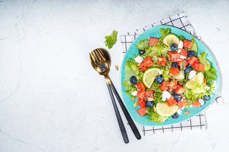 Summer watermelon salad. Fresh raw green salad with lettuce, arugula, watermelon slices, blueberry, feta cheese and honeyの写真素材