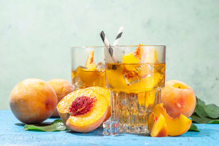 Homemade peach ice tea with ripe fresh peaches on high-colored blue wooden backgroundの写真素材
