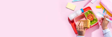 Healthy school meal, back to school concept. Children packed lunch box with balanced diet snack food - yogurt, cereal toast sandwich, apple, fresh vegetable salad, high-colored bright backgroundの写真素材